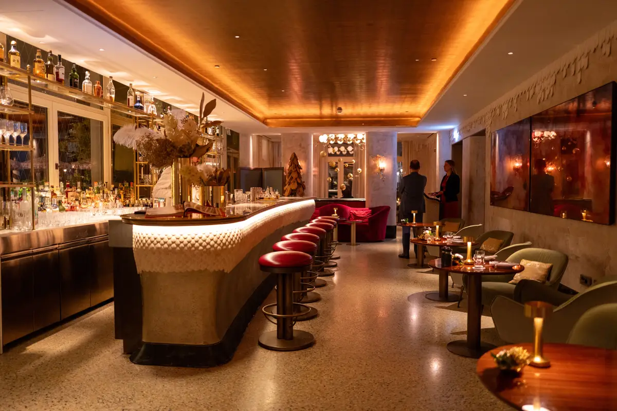 Elegant boutique hotel bar and lounge with a curved counter, red stools, and intimate seating